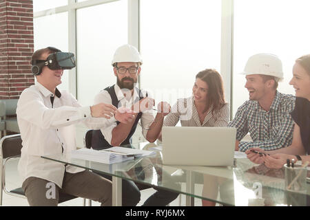 Giovani designer utilizza occhiali per realtà virtuale in una riunione in ufficio. Foto Stock
