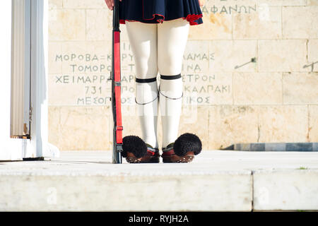 Costume tradizionale e il fucile di gambe di Evzone Guardia Presidenziale davanti al palazzo del parlamento e la tomba del Soldato sconosciuto a Atene, Grecia. Hor Foto Stock