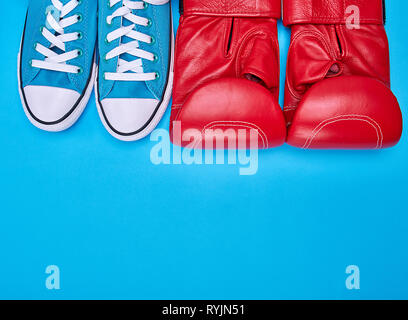 Coppia di red guantoni da pugilato e blu sneakers tessile, vista dall'alto, spazio di copia Foto Stock