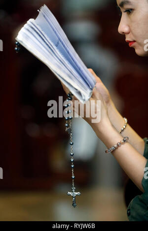 Donna cristiana della lettura della Bibbia con grani di preghiera. San Filippo chiesa ( Huyen Sy Chiesa ). Ho Chi Minh City. Il Vietnam. Foto Stock