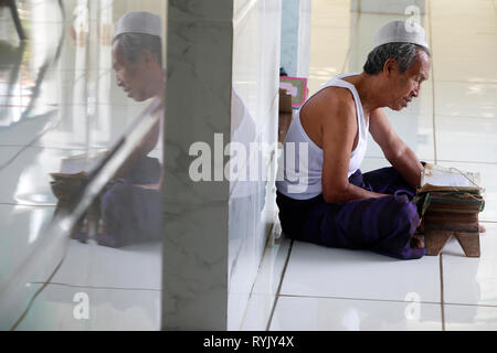 Jamiul Azhar moschea. Uomo musulmano la lettura di un vecchio Corano. Chau Doc. Il Vietnam. Foto Stock