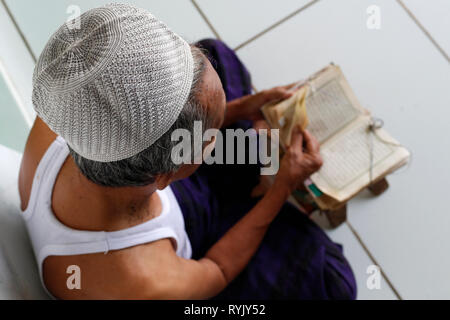 Jamiul Azhar moschea. Uomo musulmano la lettura di un vecchio Corano. Chau Doc. Il Vietnam. Foto Stock