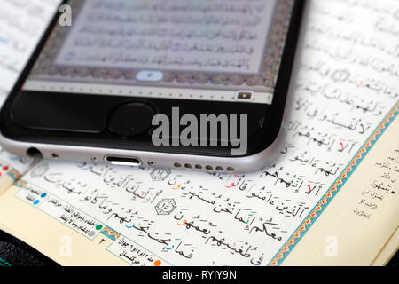 Corano digitale su uno smartphone e il Sacro Corano il libro. Close-up. Foto Stock