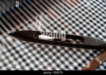 Tradizionale telaio a mano. Shuttle su un bianco e nero sciarpa. Close-up. Chau Doc. Il Vietnam. Foto Stock