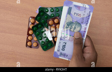 Concetto di mani della persona acquisto di pillole o compresse con la valuta indiana Foto Stock