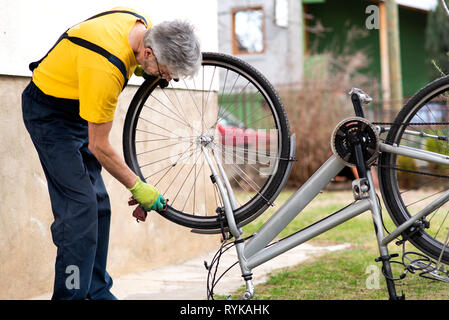 Uomo che pulisce la sua bicicletta per la nuova stagione di guida Foto Stock