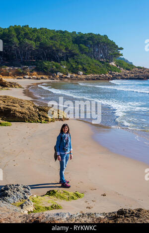 Al di sopra di vista della giovane donna che indossa abiti casual in piedi sulla spiaggia mentre cercando di telecamera in un luminoso giorno Foto Stock