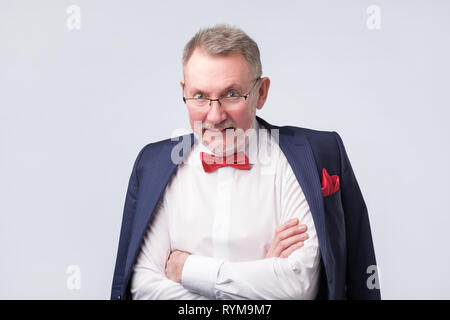 Senior uomo che indossa occhiali une tuta blu sorridente calorosamente e fiducioso. Foto Stock