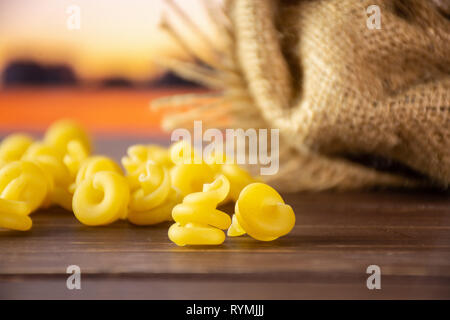 Sacco di tutta la pasta grezza funghetto varietà con un sacco di iuta con campo di autunno Foto Stock