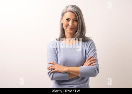 Bella grey-haired donna con bracci incrociati Foto Stock