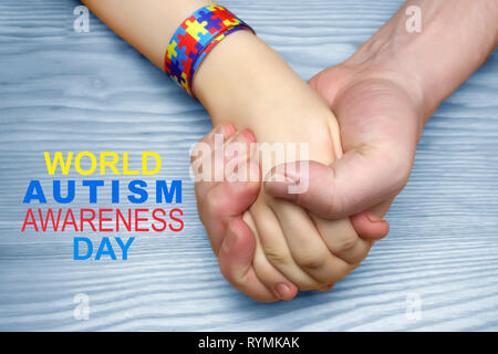 L'autismo consapevolezza dell'immagine. Padre tenendo la mano del suo bambino autistico Foto Stock