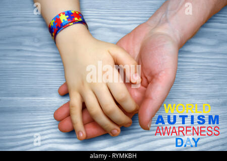 L'autismo consapevolezza dell'immagine. Padre tenendo la mano del suo bambino autistico Foto Stock