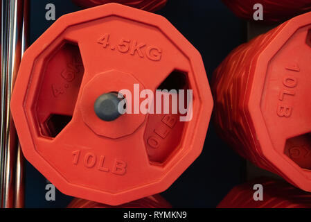 Close up red piastre di peso in una palestra vicino Foto Stock