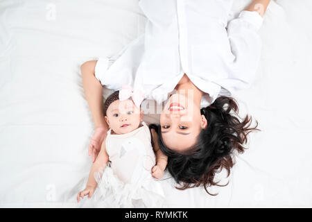 Una donna con un bambino facendo un selfie sdraiato sul pavimento in legno Foto Stock