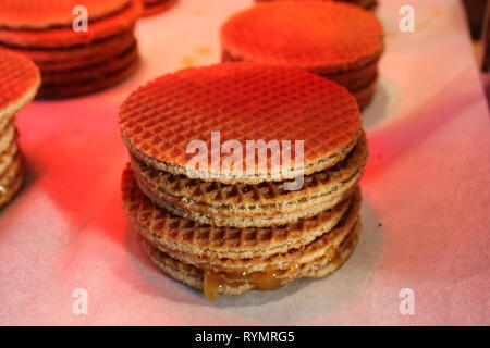 Stroopwafel tipica olandese. dolce biscotti disposti in una fila impilate una sull'altra. sfondo bianco, luce rossastra Foto Stock