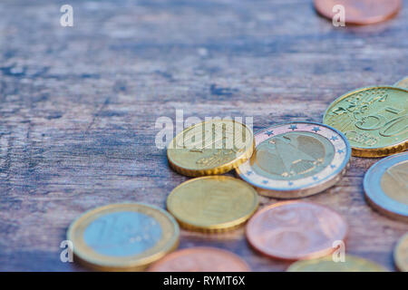 Alcune monete in euro e centesimi su un marrone la superficie di legno, macro foto a colori con uno spazio di copia Foto Stock