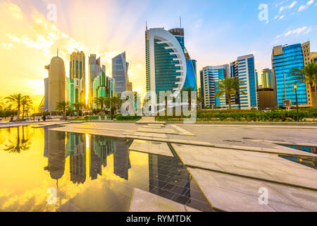 Scenario di Doha West Bay skyline al tramonto che riflette la luce in acqua del parco del centro. Vetri moderni grattacieli della skyline di Doha in Qatar Foto Stock