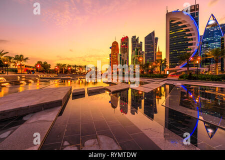 Doha West Bay alta sorge al tramonto che riflette la luce in acqua del parco del centro. I moderni grattacieli di skyline di Doha in Qatar nel Medio Oriente Foto Stock