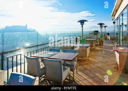 Empty street cafe con tavoli e sedie con splendida vista panoramica su sfondo vecchia città di Lubiana, mattina capitale della Slovenia. Ristorante moderno Foto Stock