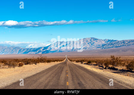 Guardando verso il basso la metà di un lungo rettilineo di strada nel deserto con nessuno in sito per miglia. Foto Stock