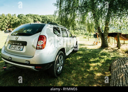 Vosges Francia - luglio 8 2018: francese rumeno Dacia Duster SUV parcheggiato sul prato in montagna francese sotto un albero di betulla con persone aventi una giovane famiglia ammirando cavallo di rancho Foto Stock