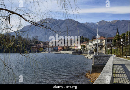 Mergozzo, Piemonte, Italia. Marzo 2019. Piacevole vista panoramica della città che si affaccia sul lago. Le fronde di un albero telaio l'immagine Foto Stock