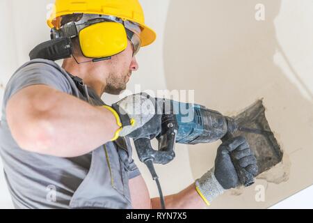 Lavoratore con martello pneumatico. Trapanare i fori in una parete per una trave di legno l'installazione. Industria edile. Foto Stock