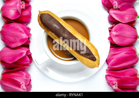 White tazza da caffè sorge su una piastra bianca con sfondo bianco vicino a multi-colore di tulipani. Primo piano Foto Stock