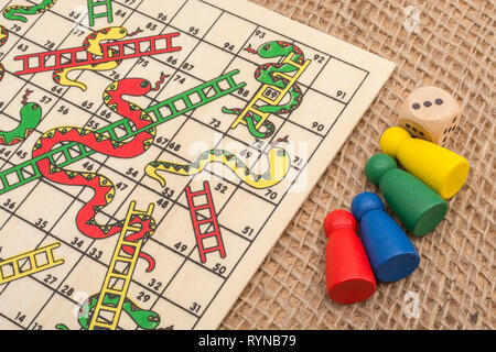 Primo piano di piccoli Snakes e Ladders gioco / gioco da tavolo per scalare scala di carriera, salire a casa scala, arrampicata sociale, lotta, alti e bassi Foto Stock