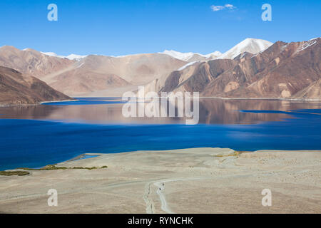 Due motociclisti in moto il bellissimo paesaggio del lago Pangong e delle montagne circostanti che si riflettono nelle acque del lago, Ladakh Foto Stock