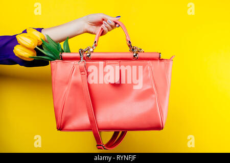 Studio shot di una donna tenendo un sacchetto con tulipani gialli su sfondo giallo Foto Stock