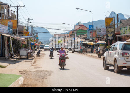 Vang Vieng, Laos - 28 dicembre 2018: la strada principale della città con il traffico, le luci di strada e segni annunciano diversi tipi delle imprese del turismo. Foto Stock