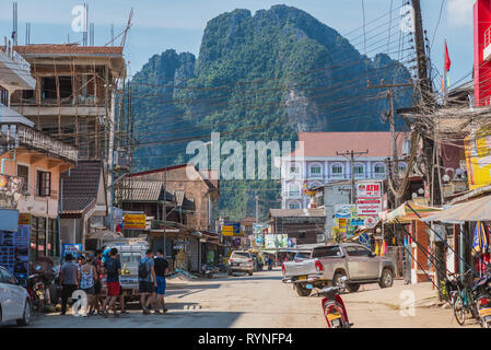 Vang Vieng, Laos - 28 dicembre 2018: una delle vie centrali della città con tutti i tipi di turismo business & una montagna di grandi dimensioni in background. Foto Stock