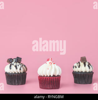 Tre mini cupcake cioccolato muffin su rosa spazio di copia Foto Stock