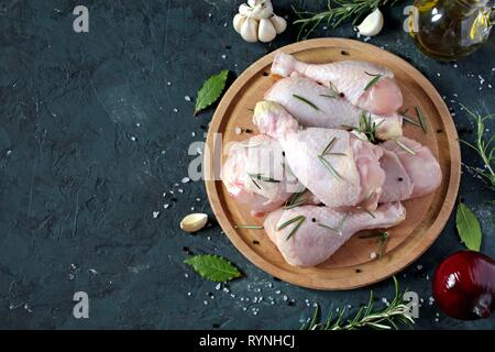 Materie non cotti le cosce di pollo con gli ingredienti per cucinare, bacchette sulla tavola di legno. Vista da sopra con copia spazio. Foto Stock