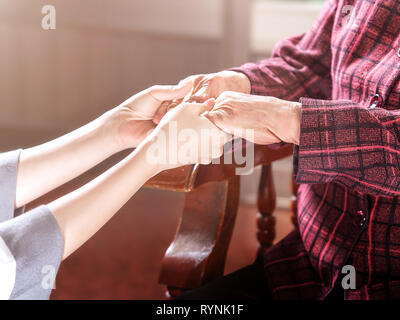 Asia Teenage ragazza giovane badante tenendo nonnina mani, concetto di aiutare la cura per gli anziani la vita con sfondo scuro, close up, copia spazio, ritagliato Foto Stock