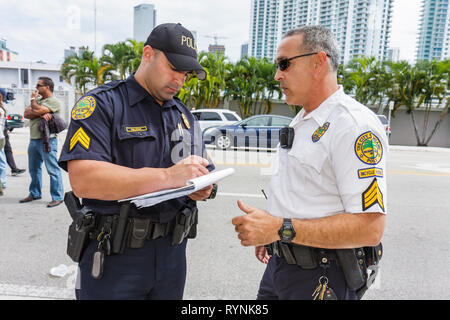 Miami Florida,uomo ispanico uomini maschio,polizia,poliziotto,ufficiale,uniforme,lavoro,lavoro,dipendenti lavoratori dipendenti personale,pubblica sicurezza,proteggere,sicurezza,parlare Foto Stock