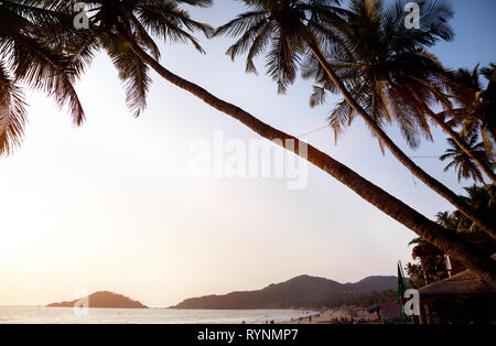 Bella vista panoramica del tramonto tropicale spiaggia con bungalow e palme di cocco a Palolem in Goa, India Foto Stock