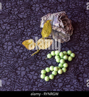 Rosa artificiale con perline di malachite su sfondo tessili. Foto Stock