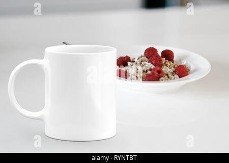 Tazza bianca accanto a una ciotola di cereale. La soluzione ideale per le aziende di vendita mockups mug Foto Stock