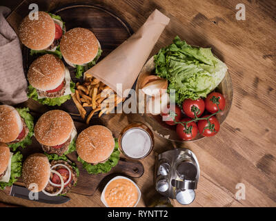 Vista dall'alto di diversi fast food su un tavolo di legno. Le carni bovine. Pomodori freschi. Il cibo è ottimo. Foto Stock