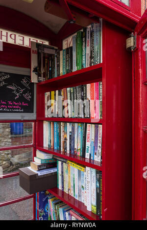 Il vecchio telefono rosso chiosco convertiti per utilizzare come un libro di exchange nel villaggio di Collingtree, Northamptonshire, Regno Unito Foto Stock
