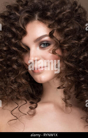 Bella bruna ragazza con una perfettamente i capelli ricci e classic per il make-up. Bellezza viso. Foto Stock