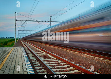 Ferrovia viaggi e trasporti industria concetto di business: estate vista notturna di alta velocità per i passeggeri in partenza in treno dalla stazione ferroviaria platform Foto Stock