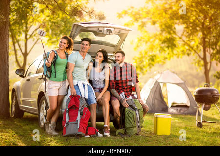 Un gruppo di giovani arrivati sul viaggio di campeggio e rendendo selfie ritratto Foto Stock