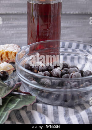 Frutti di bosco surgelati in una ciotola di vetro, closeup, un bicchiere di succo rosso. Foto Stock