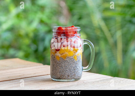 Latte di Mandorla chia pudding con fragole fresche e mango in un vasetto di vetro mug. Vegan materie prima colazione. Semi di Chia e taglio freschi frutti e bacche desser Foto Stock