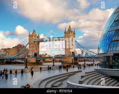 Londra, Inghilterra - Marzo 10, 2019: la splendida vista del Tower Bridge da più Luogo di Londra con i turisti a piedi lungo il fiume al tramonto Foto Stock