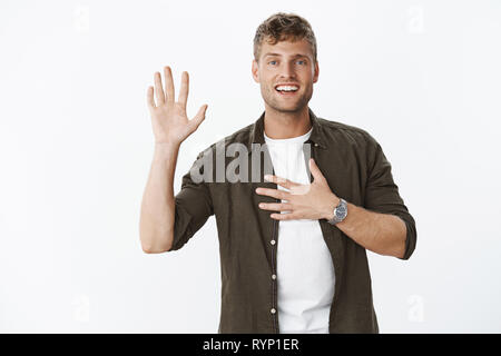 Io giuro di. Ritratto di amichevole-cercando affascinante e carismatico maschile matura maschio con capelli biondi sollevamento palm e tenendo la mano sul cuore come Foto Stock