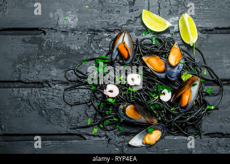 Cucina mediterranea. Spaghetti al nero di seppia e vongole. Nero su sfondo rustico.